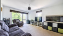 Living room with sofas, TV, stprage cupboards and large windows.
