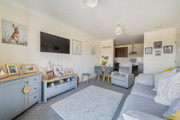 Open-plan living area with sofas, a TV and dining space, leading into kitchen.