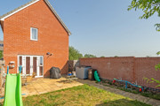 Rear garden with lawn, patio area and brick house exterior.