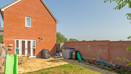 Rear garden with lawn, patio area and brick house exterior.