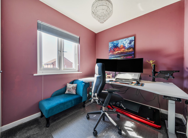 Home office with desk, computer setup, chair and window.