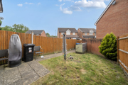 Garden with paving slabs, lawn, wooden fence, and bins near the patio.