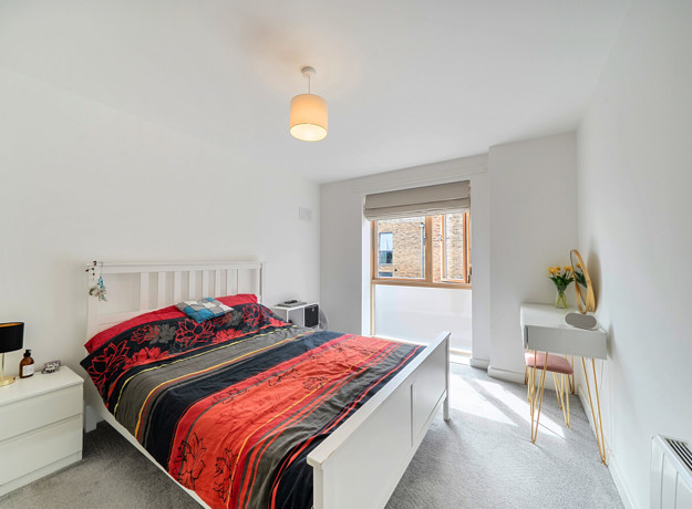 Double bedroom with bedside tables, vanity unit and window.