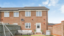 Rear view of brick house with fenced garden and small patio area.