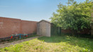 Enclosed garden with grass lawn, wooden shed and surrounding fences.