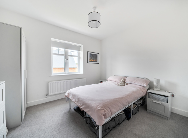 Bedroom with double bed, bedside table, window, and light grey decor.