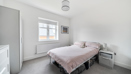 Bedroom with double bed, bedside table, window, and light grey decor.