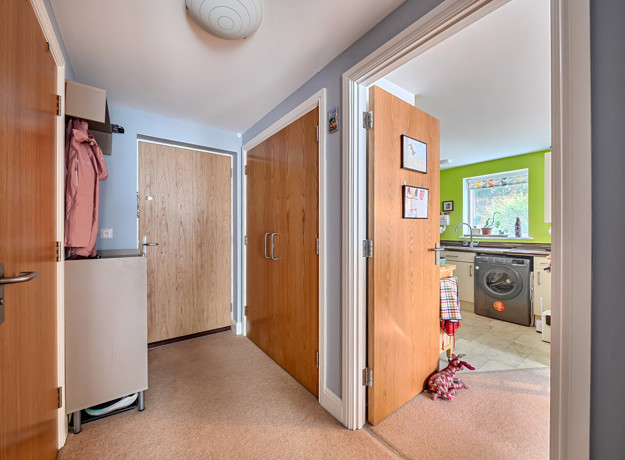 Hallway with doors and view into the kitchen.