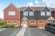 Row of brick and render terraced houses with parked car on a driveway.