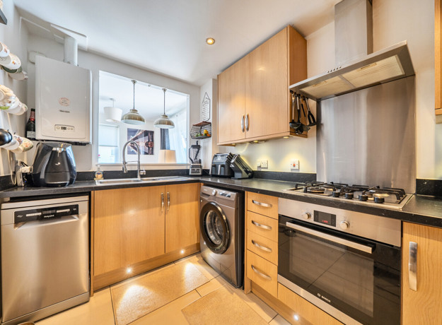 Kitchen with wooden cabinets, appliances, window and sink.