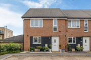 Brick semi-detached house with driveway, small front garden and blue sky.