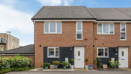 Brick semi-detached house with driveway, small front garden and blue sky.