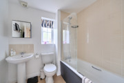 Bathroom with sink, toilet and bathtub with shower screen.