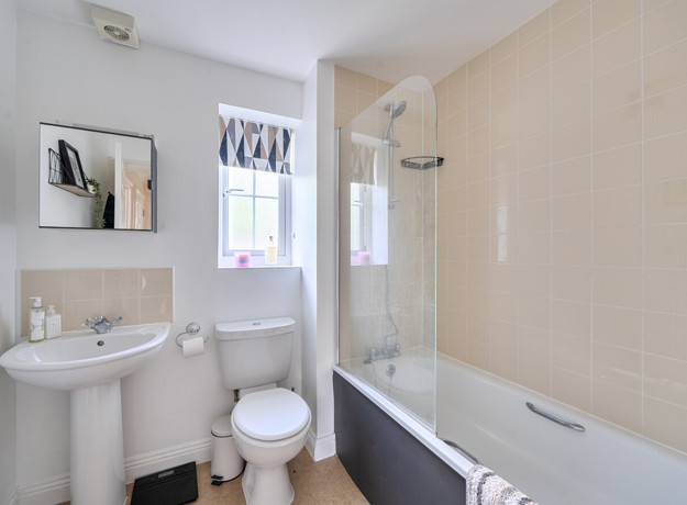 Bathroom with sink, toilet and bathtub with shower screen.