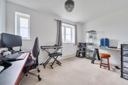 Home office with desks, computers, chair and shelving units near window.