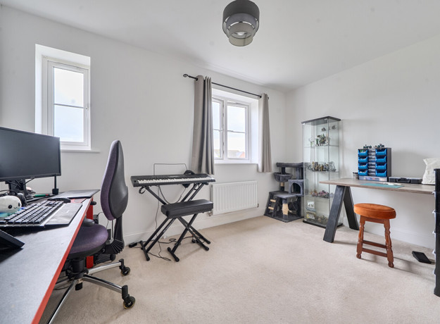 Home office with desks, computers, chair and shelving units near window.