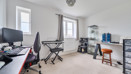 Home office with desks, computers, chair and shelving units near window.