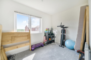Bedroom with exercise equipment, dismantled bed and a large window.