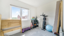 Bedroom with exercise equipment, dismantled bed and a large window.