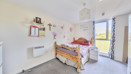 Bedroom with bed, desk area and window bringing in natural light