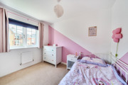 Child’s bedroom with pink accents, bed, and window.