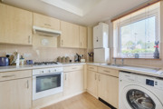 Kitchen with cabinets, oven, sink, boiler, washing machine and window.