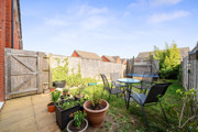 Enclosed garden patio and lawn with potted plants, outdoor table and chairs