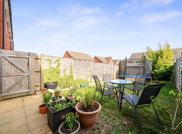 Enclosed garden patio and lawn with potted plants, outdoor table and chairs