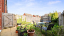 Enclosed garden patio and lawn with potted plants, outdoor table and chairs