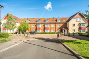 Exterior view of a three stories apartment building with red brick facade and landscaped grounds