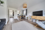 Open-plan living and dining area with a sofa, television and dining table.