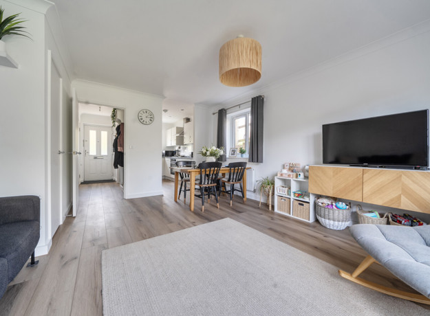 Open-plan living and dining area with a sofa, television and dining table.