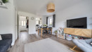 Open-plan living and dining area with a sofa, television and dining table.