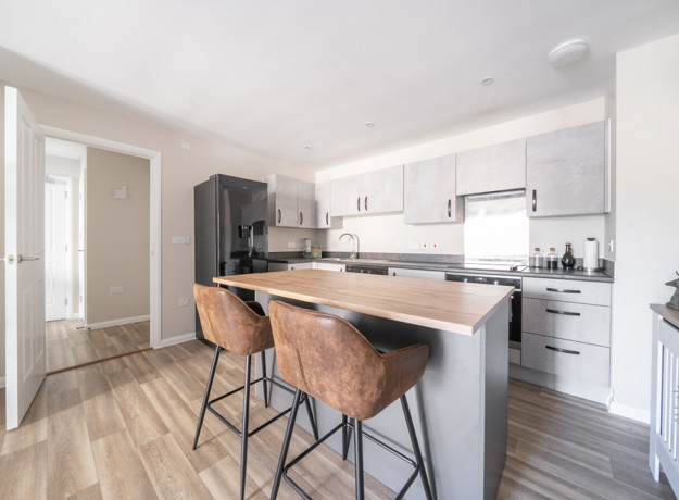 Kitchen with breakfast bar, stools and integrated appliances.