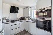 White kitchen with integrated appliances, hob, sink and wall-mounted extractor fan.