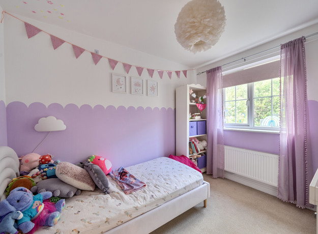 Children bedroom with bed, toys, purple decor and window.