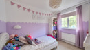 Children bedroom with bed, toys, purple decor and window.
