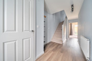 Hallway with wooden-effect flooring, stairs and doors leading to rooms.