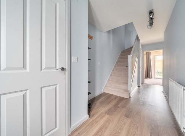 Hallway with wooden-effect flooring, stairs and doors leading to rooms.