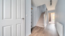 Hallway with wooden-effect flooring, stairs and doors leading to rooms.