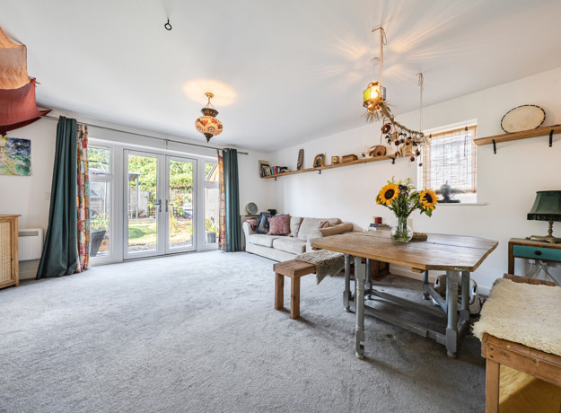 Open-plan living and dining area with table, chairs and patio doors.