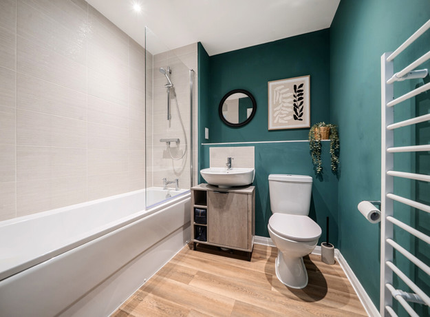 Bathroom with bath, toilet, sink unit and towel rail.