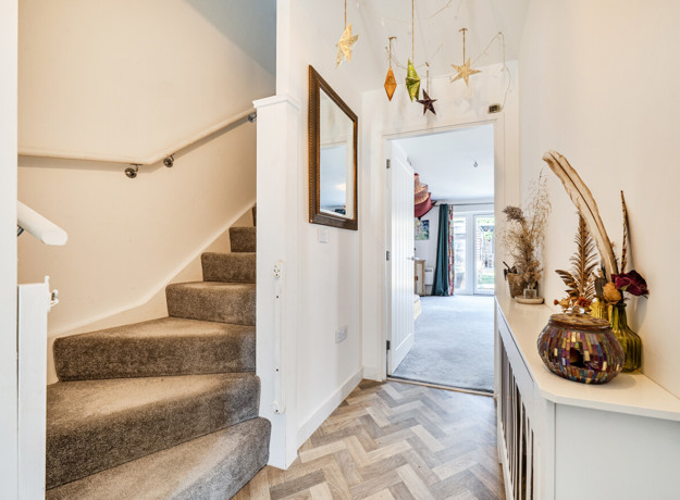 Hallway with carpeted stairs, console table and front door view.