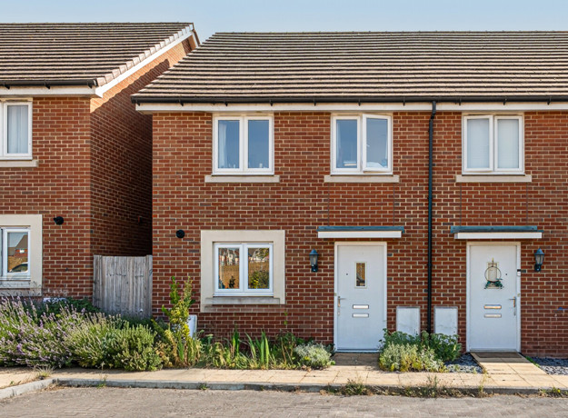 Front elevation of a red brick terraced house with neighbouring properties.