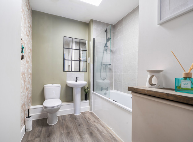 Bathroom with bathtub, shower screen, toilet, and sink.