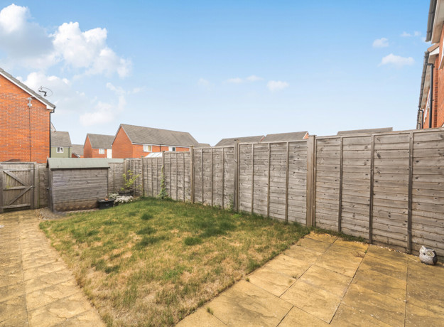 Rear garden with lawn, patio area, shed and fenced boundaries.