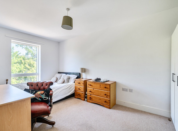 Bedroom with a bed, window, chest of drawers, and desk.