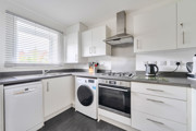 Kitchen with white cabinets, oven, washing machine and countertop appliances.