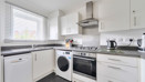 Kitchen with white cabinets, oven, washing machine and countertop appliances.