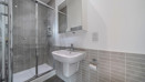 Modern shower room with glass shower enclosure, wall-mounted sink, toilet, and tiled walls